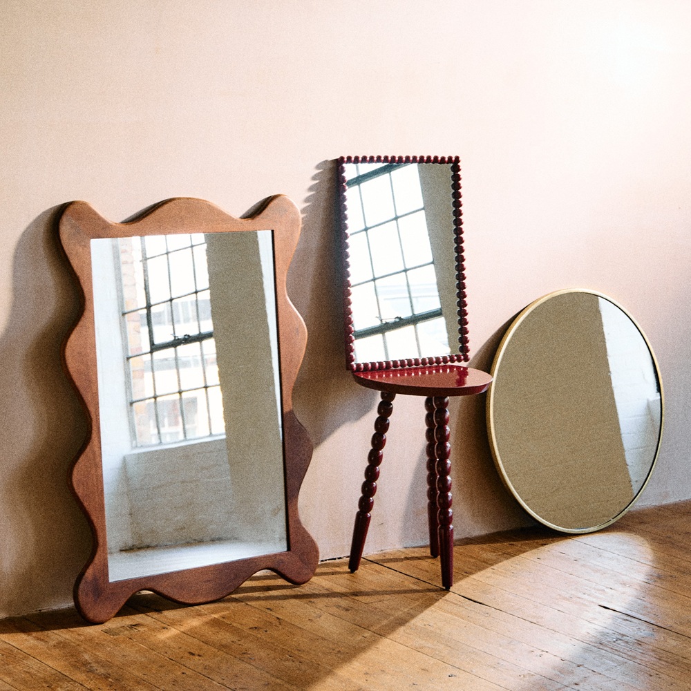 Three wooden mirrors against a wall