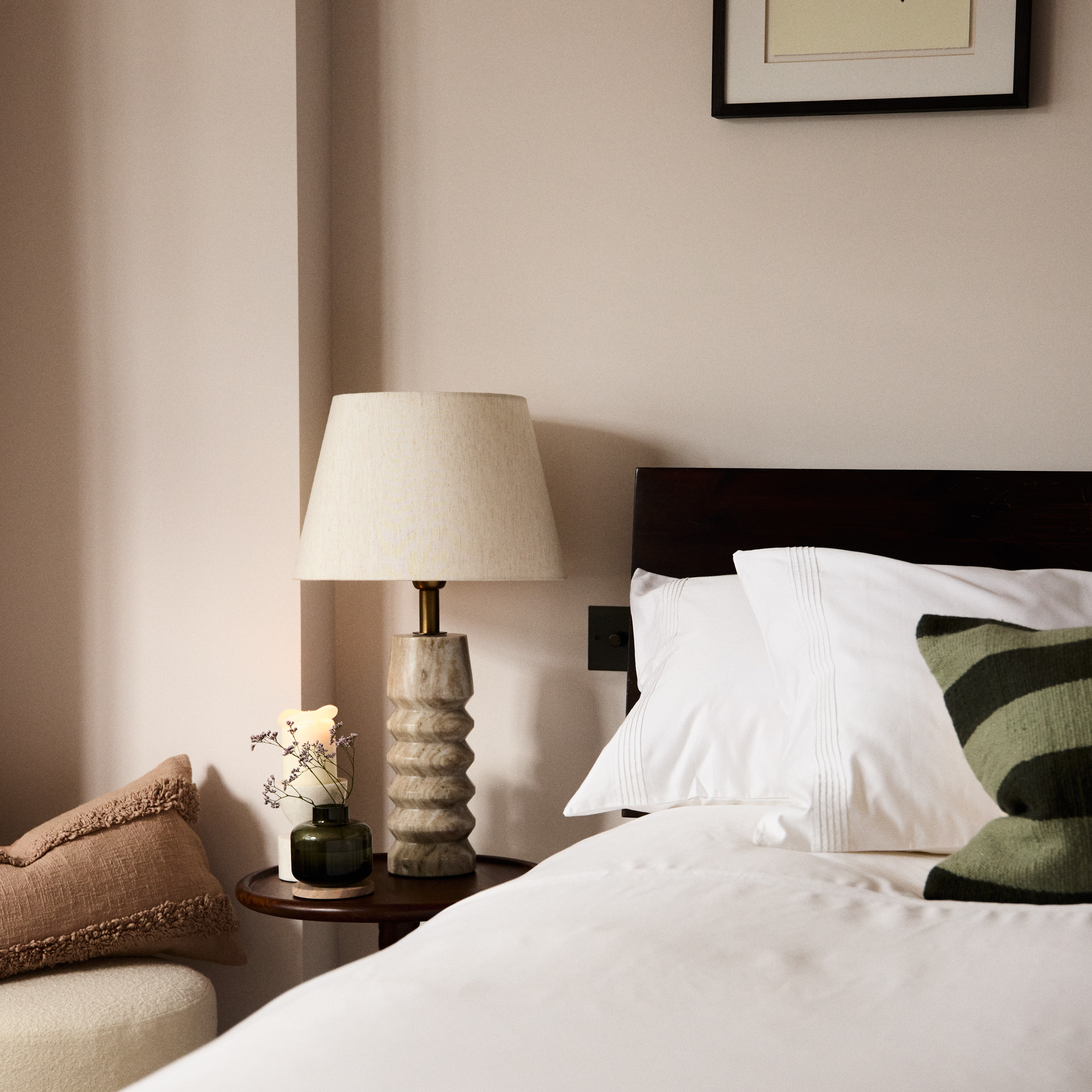 A lamp on a table next to bed