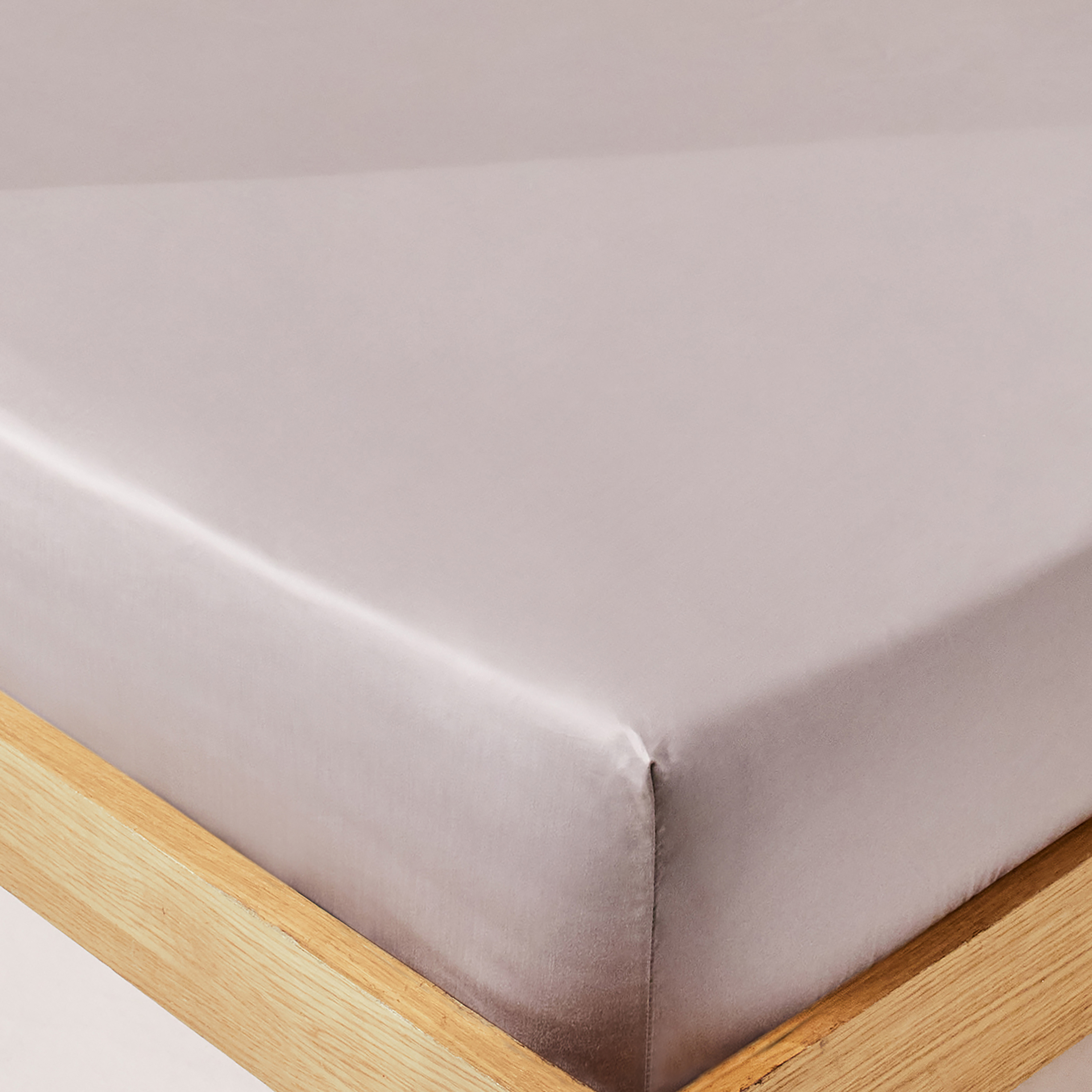 Grey coloured high thread count cotton bed sheet on wooden bed