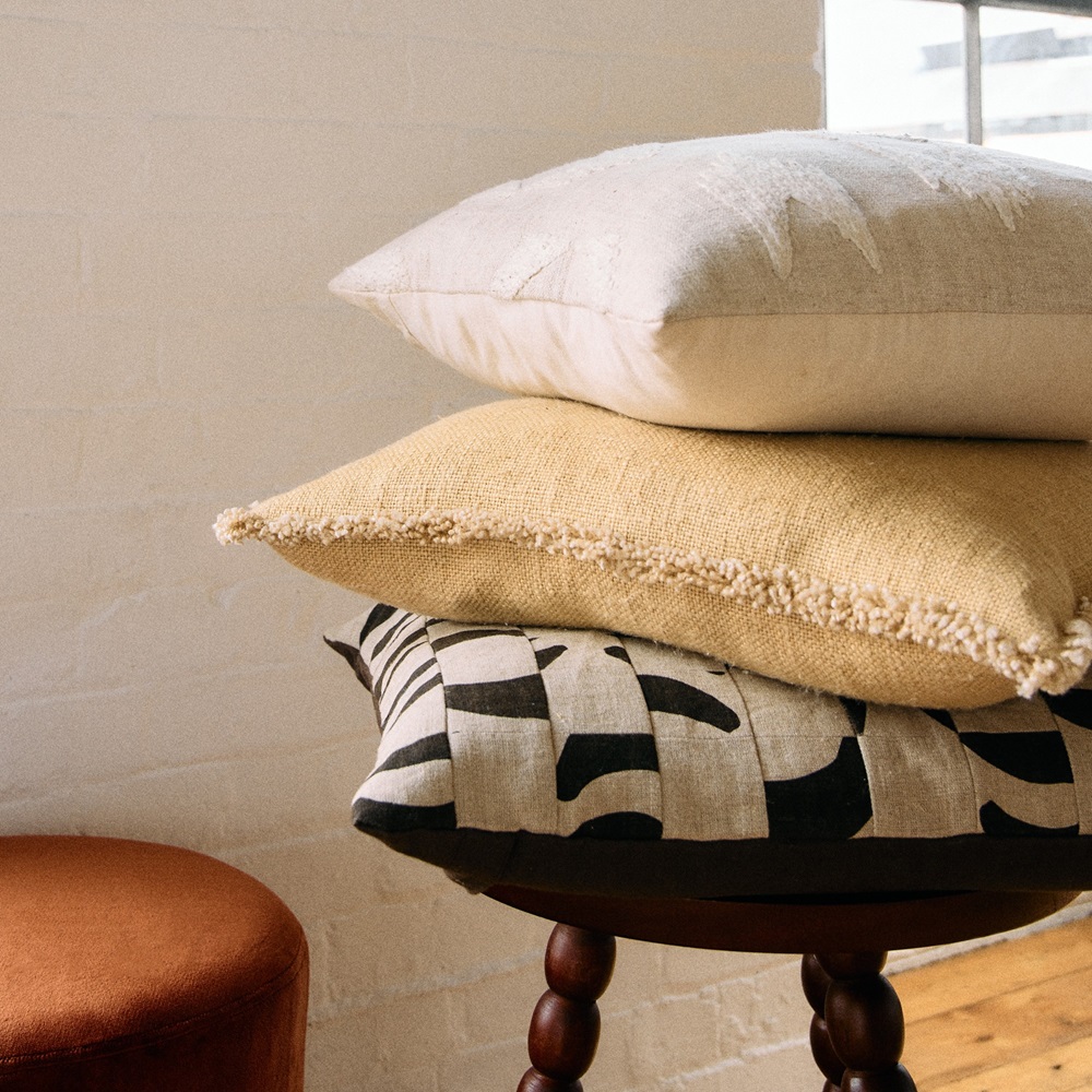 A trio of natural fibres cushions stacked on a chair