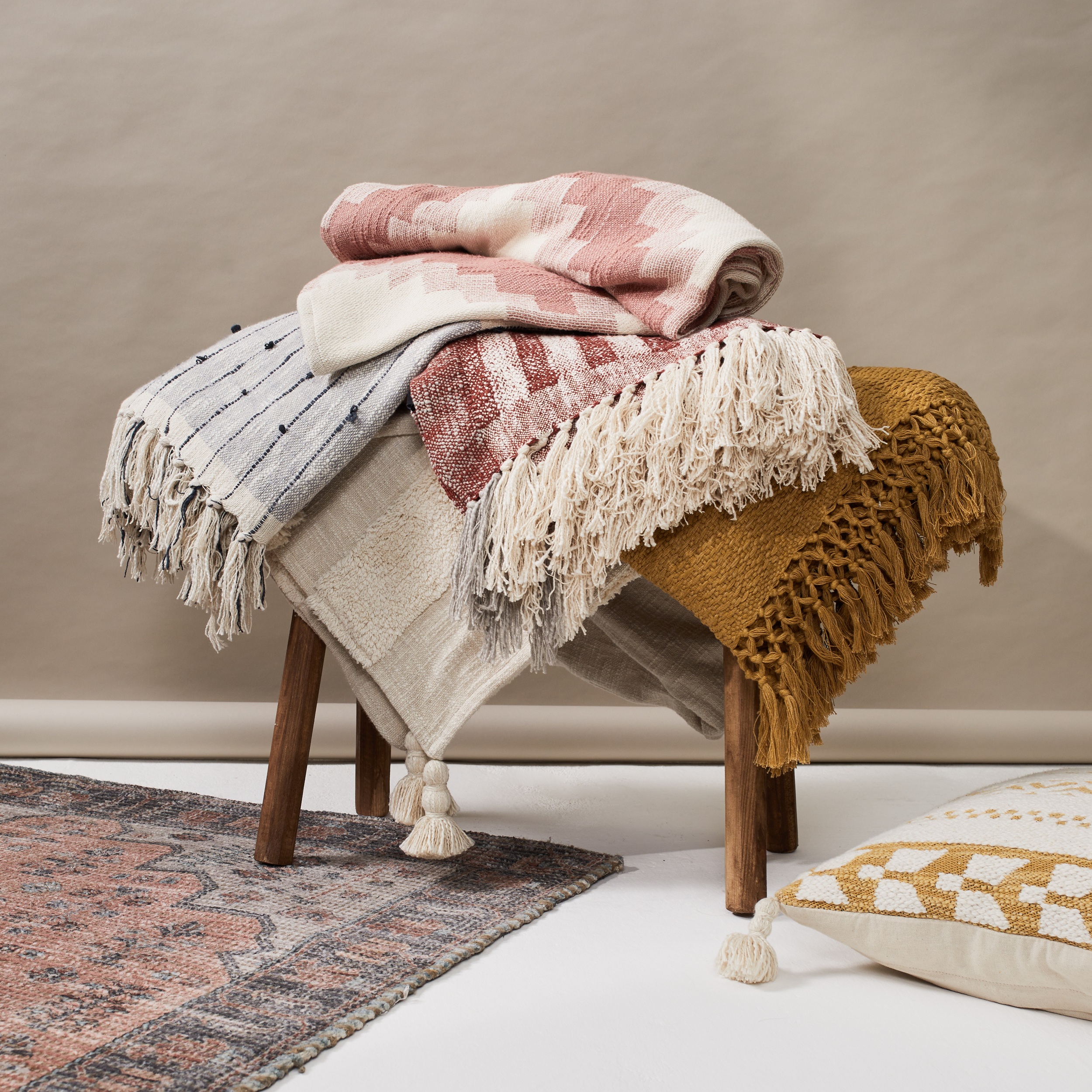 A pile of cotton woven rugs in natural colours