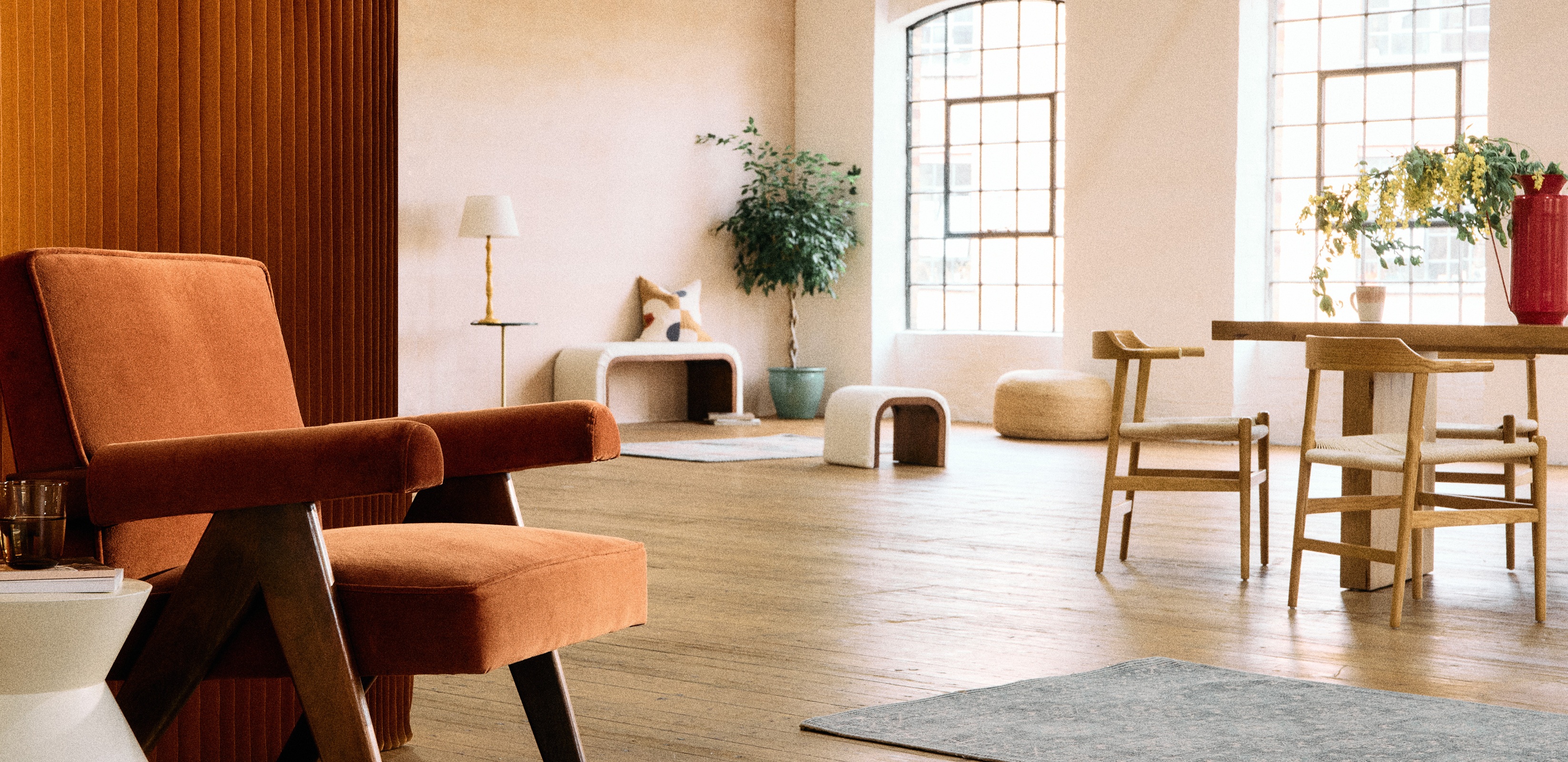 Rust velvet armchair in a living room with a table and chairs in the background