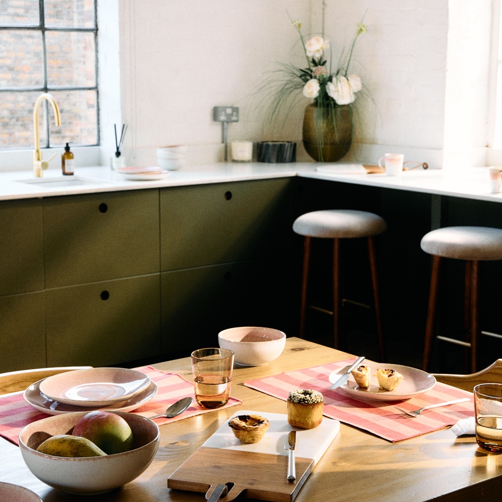 A kitchen table with stoneware ceramic tableware and home accessories in the background