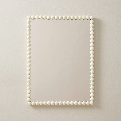 A stylish cream mirror on a plain wall background