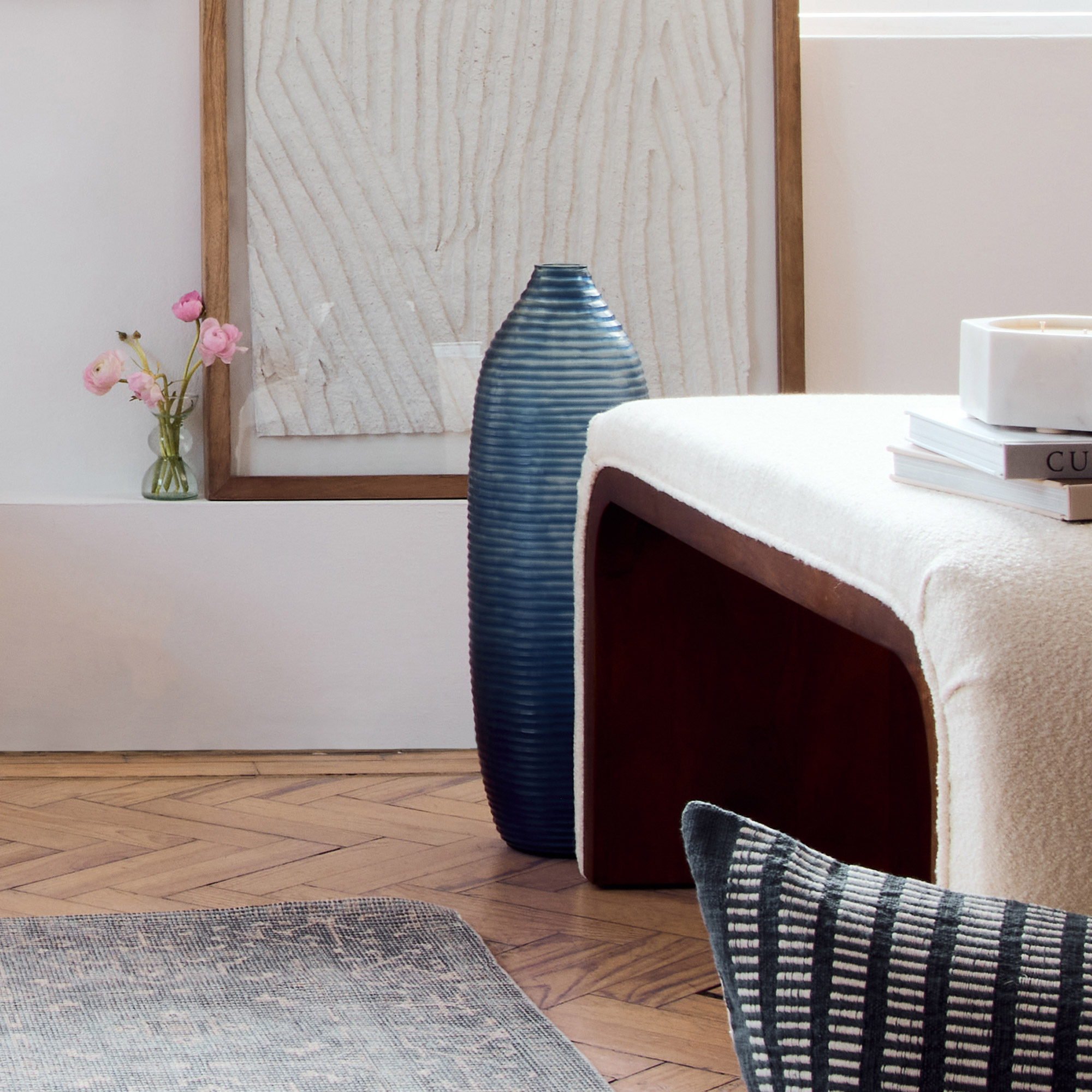 Picture of a living-room with a glass blue vase next to a bench