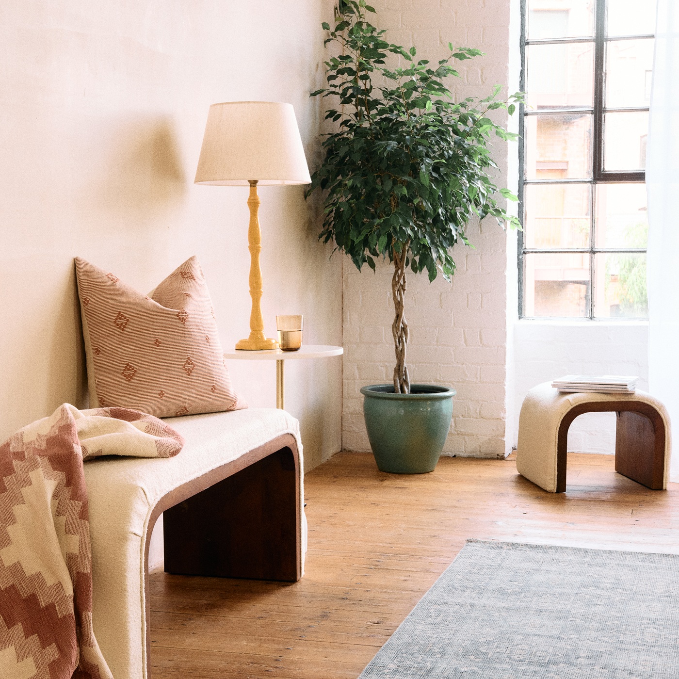 A white boucle bench with cushions in a living room