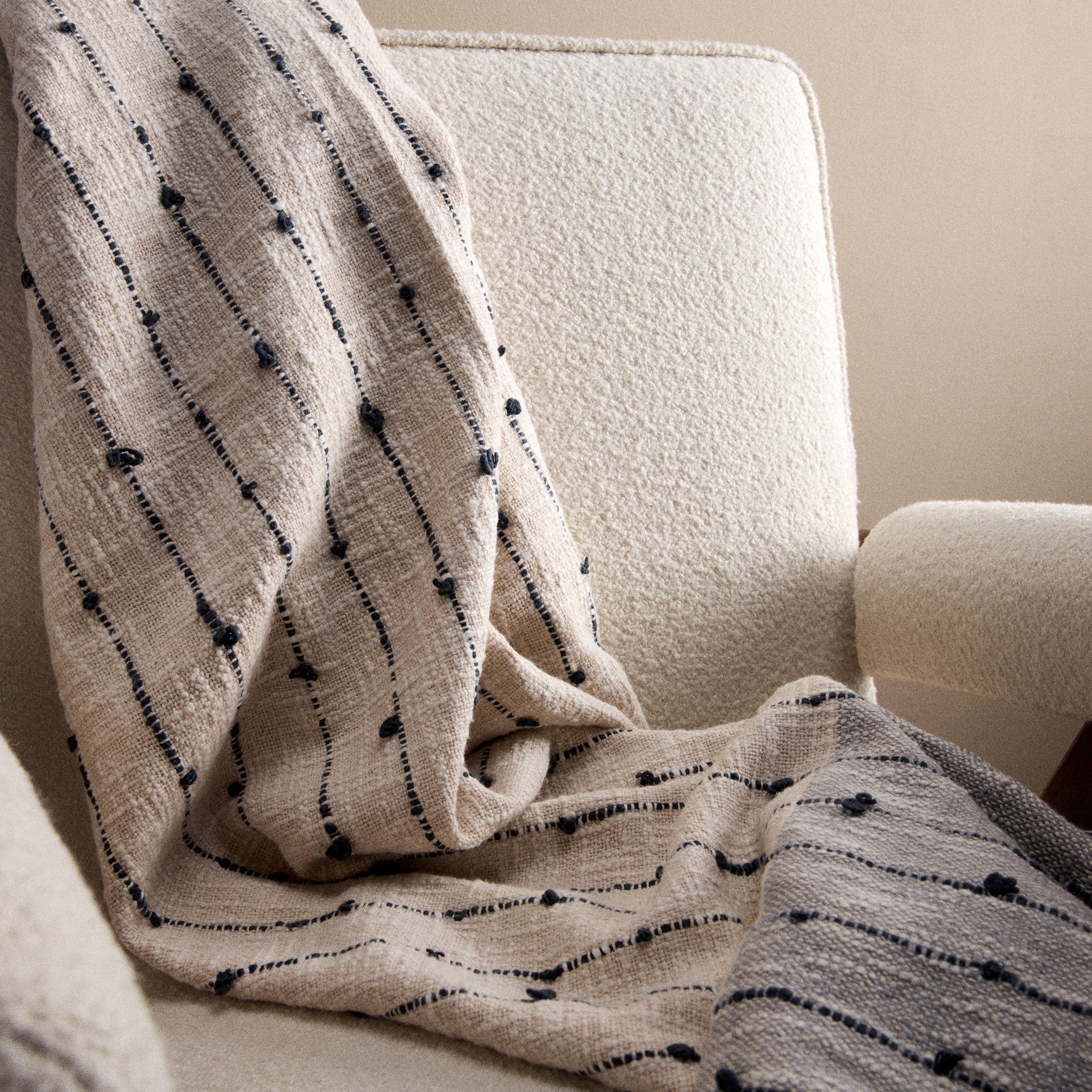 A pile of cotton woven rugs in natural colours