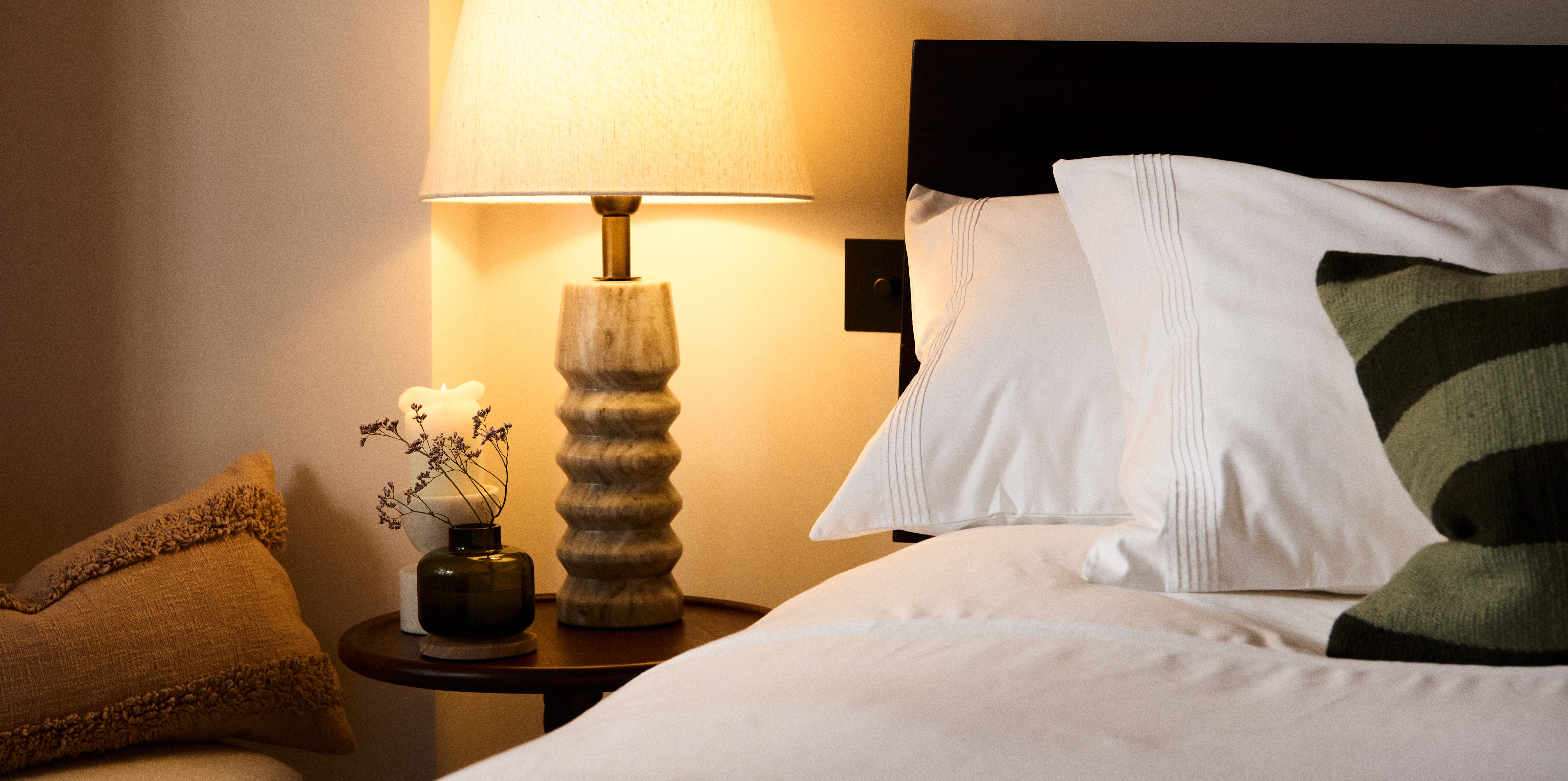 White cotton bed linen with a wooden lamp on a wooden bedside table