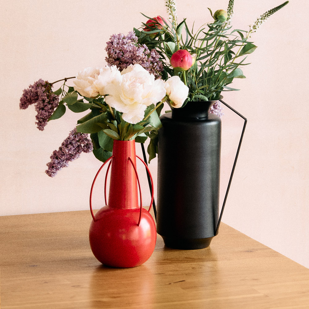 Two vases with flowers against a wall