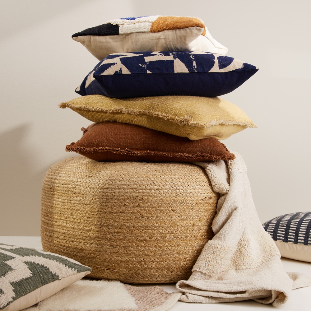 A pile of colourful footstools, woven cushions and throws