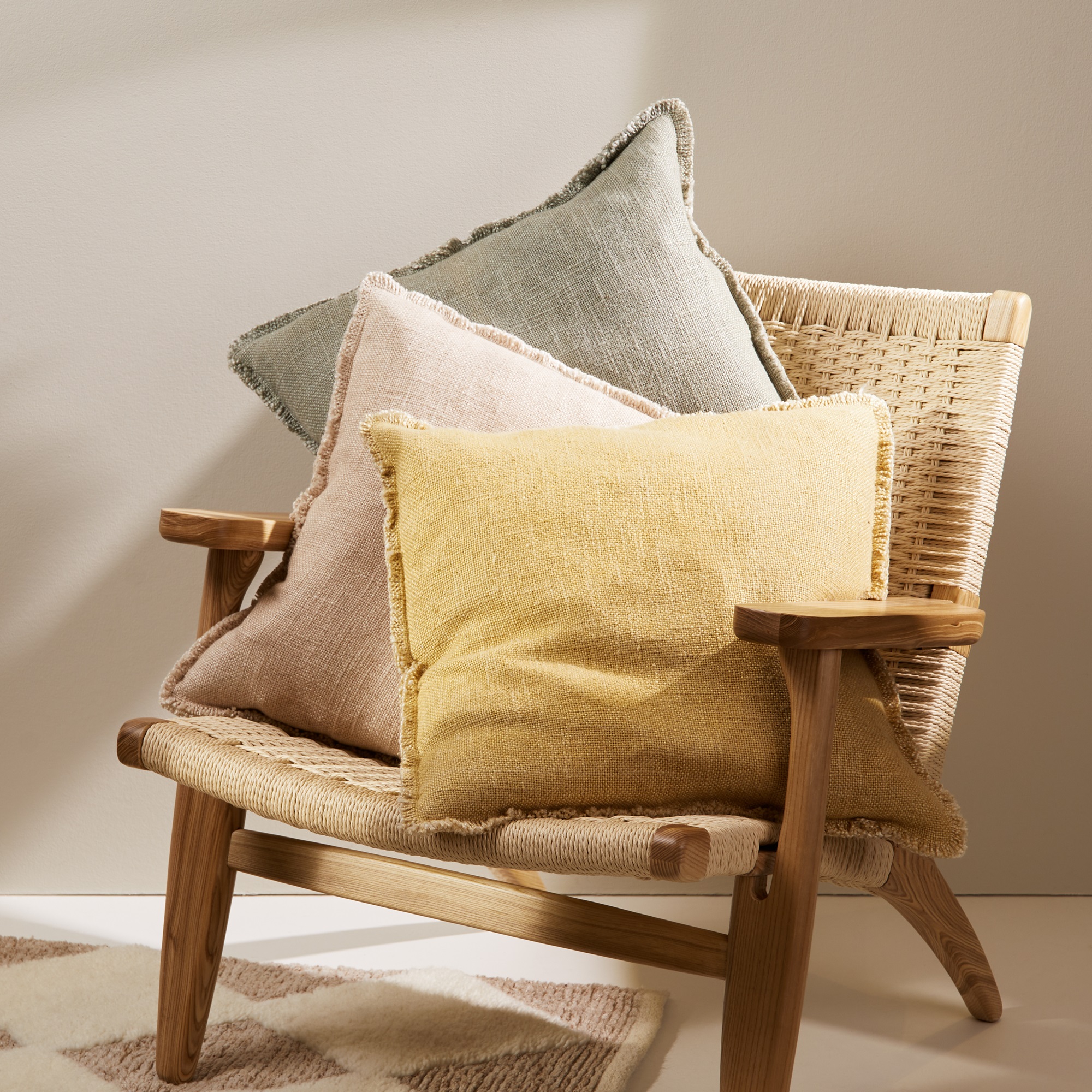 A set of three colourful cushions on an armchair