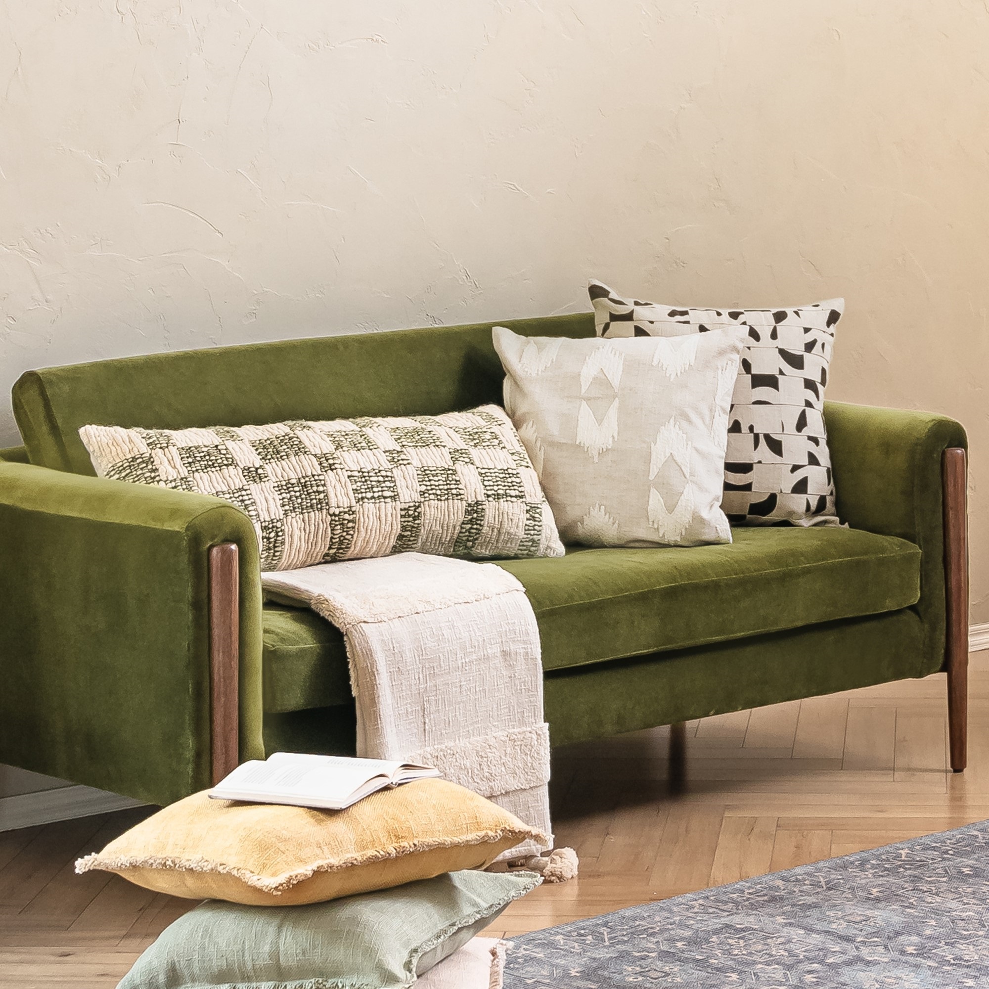 A set of cushions and throws on a green velvet sofa