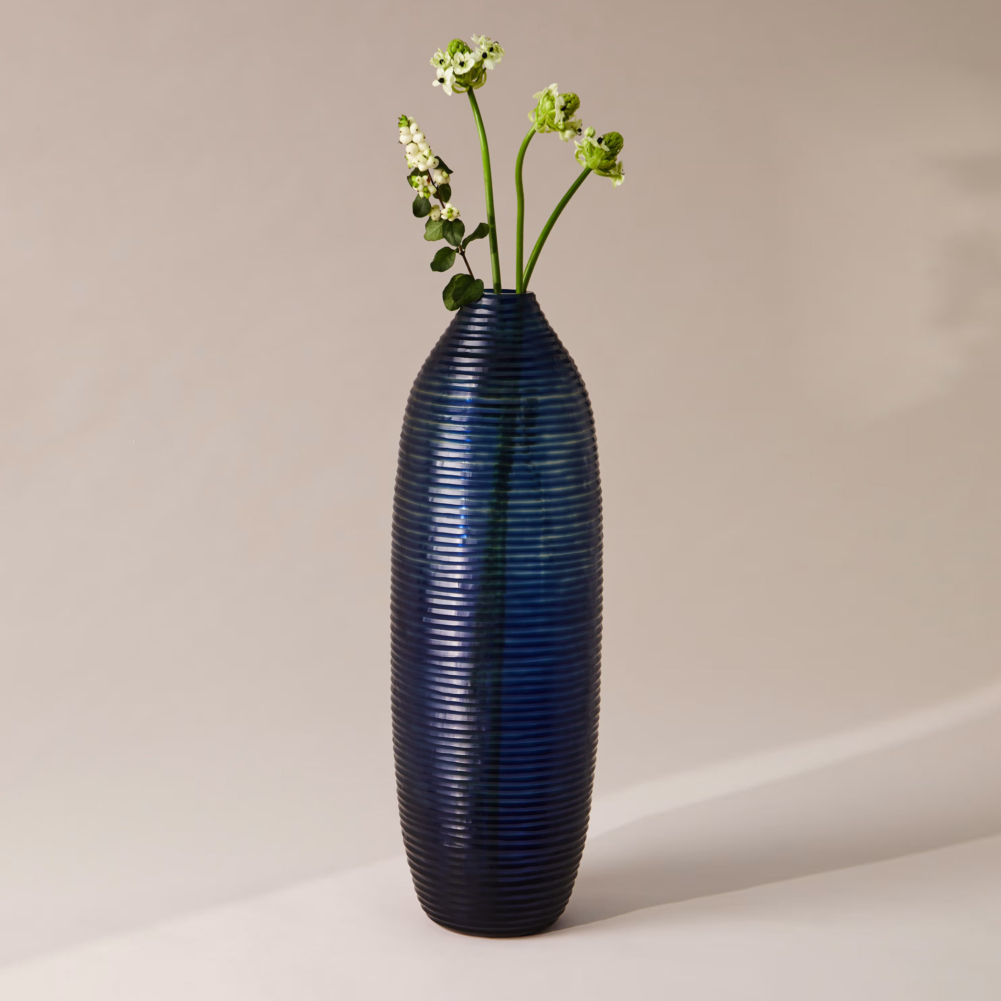 A tall blue glass vase with flowers