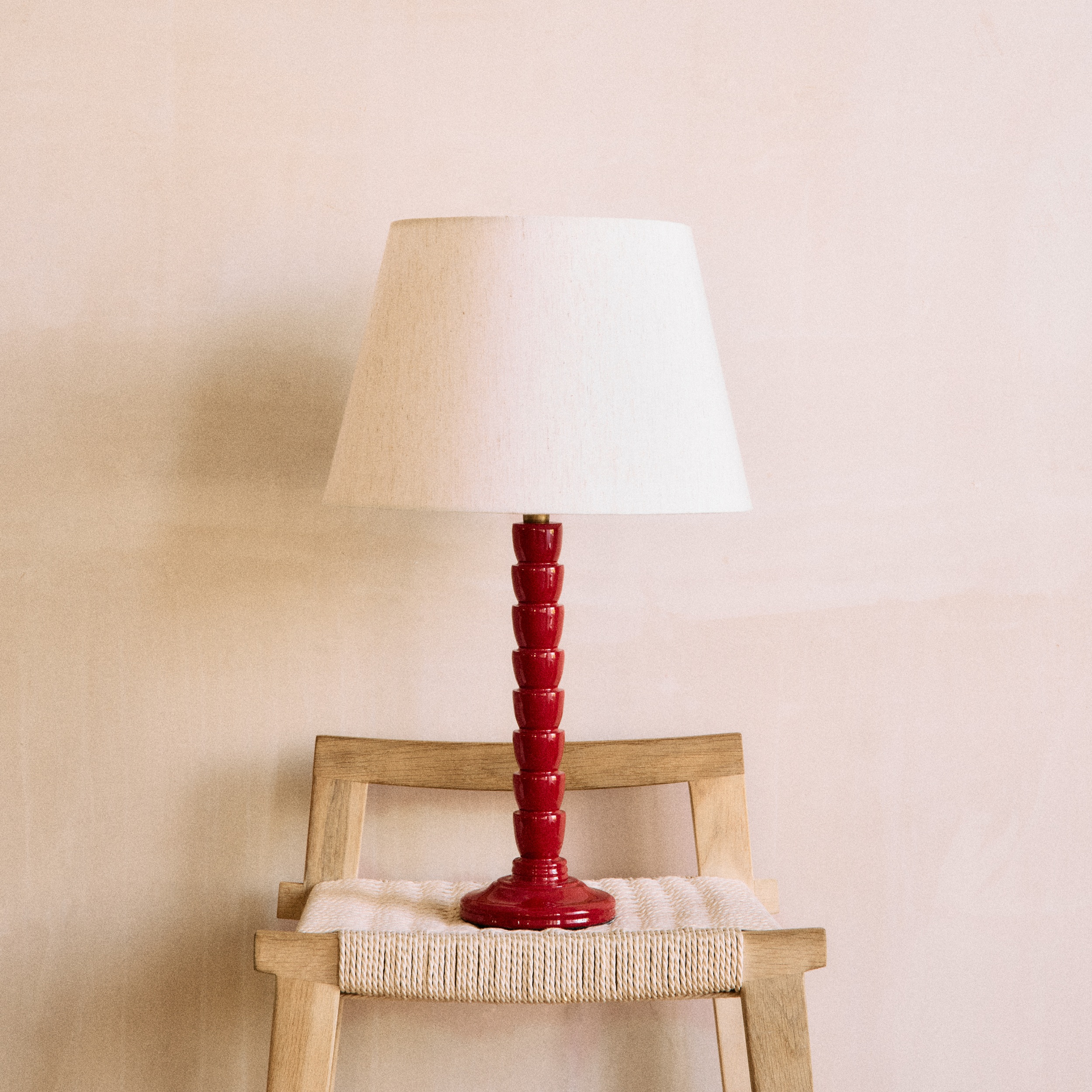 A red wooden lamp with a white lampshade on a wooden chair