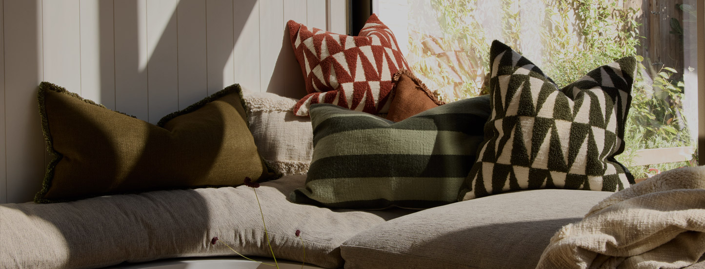 Rust velvet armchair in a living room with a table and chairs in the background